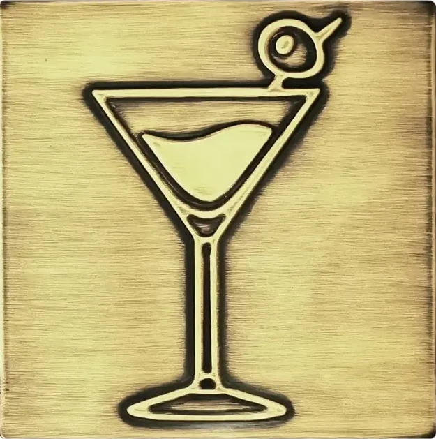 A glass of martini with olive on brass tile