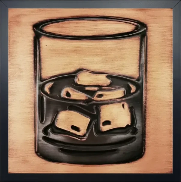 A glass of whiskey on copper tile in wooden frame